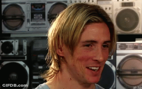A Man With Long Blonde Hair Is Smiling In Front Of A Row Of Boomboxes GIF