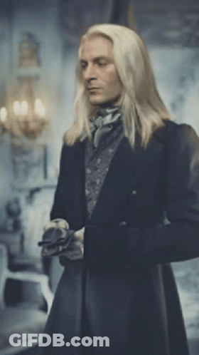 A Man With Long Blonde Hair Is Standing In A Room GIF