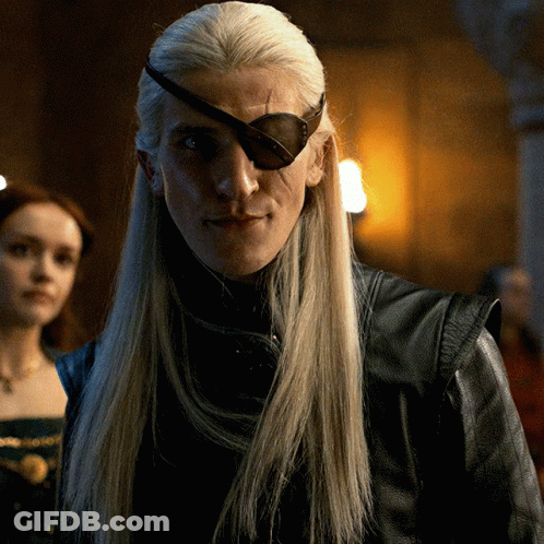 A Man With Long Blonde Hair Wearing A Black Leather Jacket And An Eye Patch GIF