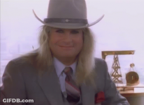 A Man With Long Blonde Hair Wearing A Cowboy Hat And Suit GIF