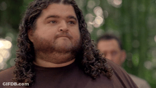 A Man With Long Curly Hair And A Beard Looks To The Side GIF