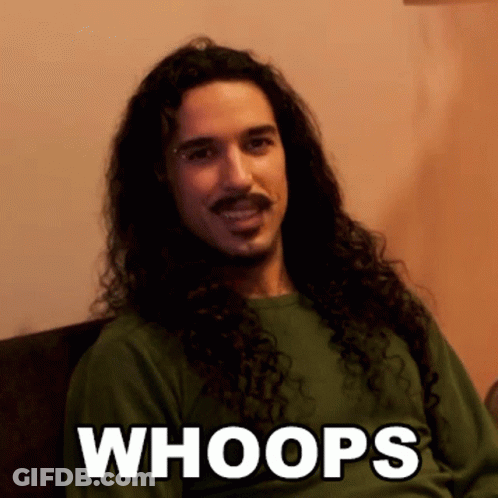 A Man With Long Curly Hair And A Mustache Is Wearing A Green Shirt That Says " Whoops " GIF