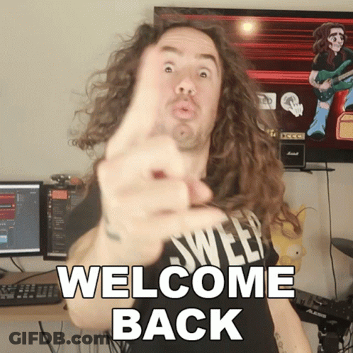 A Man With Long Curly Hair Is Pointing At The Camera With The Words Welcome Back Below Him GIF