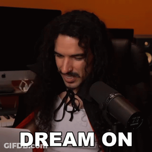 A Man With Long Curly Hair Is Sitting In Front Of A Shure Microphone GIF