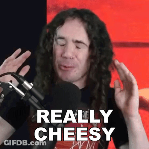 A Man With Long Curly Hair Is Talking Into A Microphone And Says Really Cheesy GIF