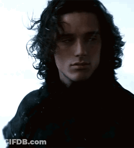 A Man With Long Curly Hair Is Wearing A Black Shirt GIF