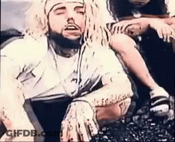 A Man With Long Dreadlocks And A Beard Is Sitting On The Ground With His Eyes Closed . GIF