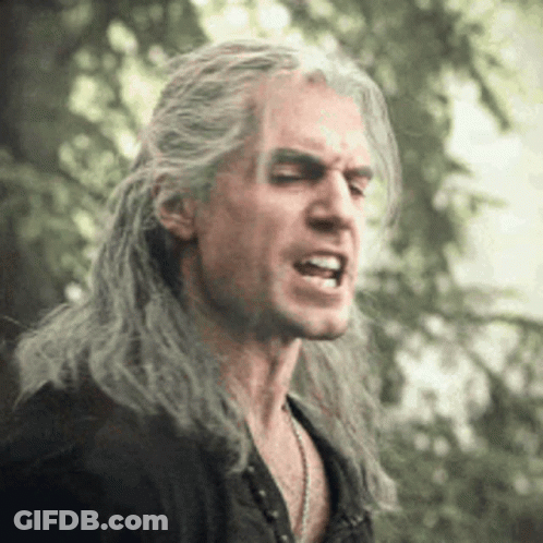 A Man With Long Gray Hair Is Making A Funny Face With His Mouth Open . GIF