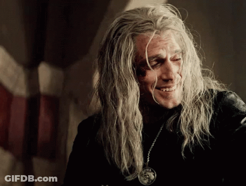 A Man With Long Grey Hair Is Smiling And Wearing A Pendant GIF