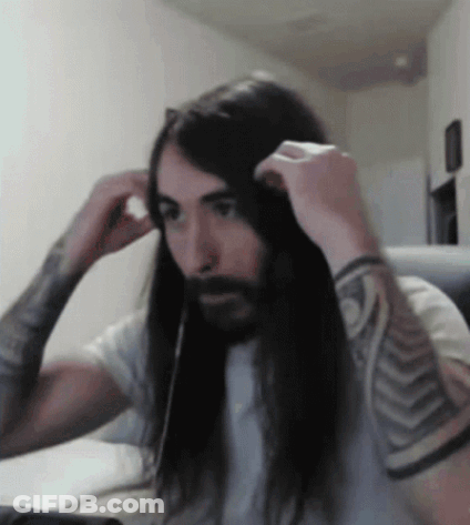 A Man With Long Hair And A Beard Adjusts His Headphones GIF