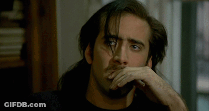 A Man With Long Hair And A Beard Has His Hand On His Face GIF