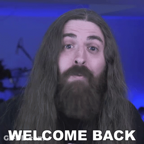 A Man With Long Hair And A Beard Has The Words Welcome Back On His Face GIF