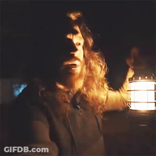 A Man With Long Hair And A Beard Is Holding A Lantern In His Hand GIF