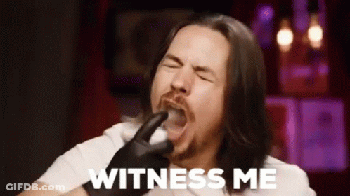 A Man With Long Hair And A Beard Is Holding A Pipe In His Mouth And Saying `` Witness Me '' . GIF