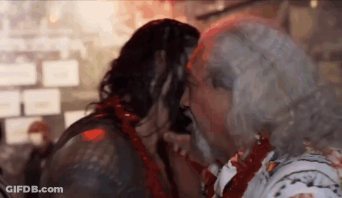 A Man With Long Hair And A Beard Is Kissing A Woman . GIF