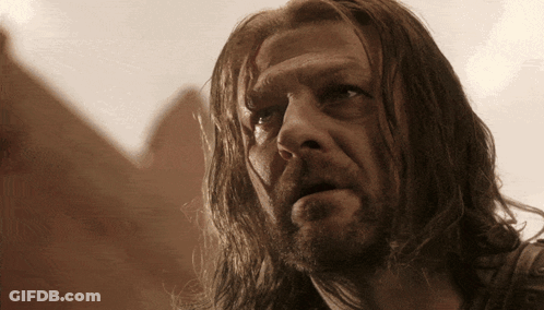 A Man With Long Hair And A Beard Is Looking At Something GIF