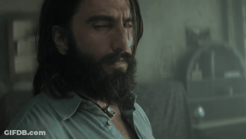 A Man With Long Hair And A Beard Is Looking Down GIF