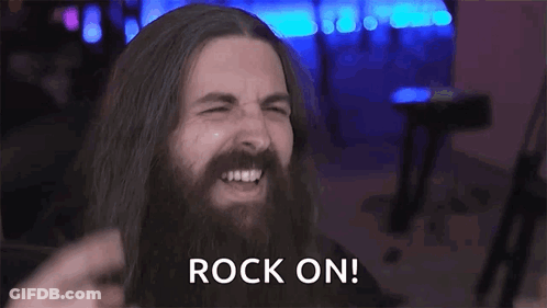 A Man With Long Hair And A Beard Is Making A Devil Horns Sign With His Hands . GIF