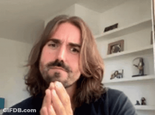 A Man With Long Hair And A Beard Is Making A Funny Face GIF