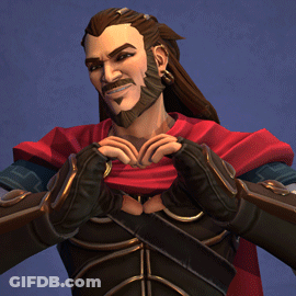 A Man With Long Hair And A Beard Is Making A Heart With His Hands GIF
