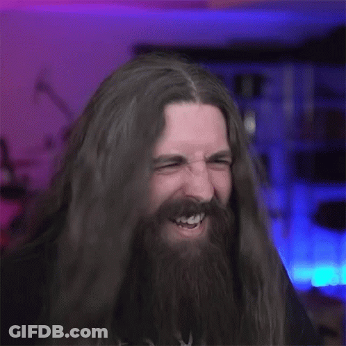 A Man With Long Hair And A Beard Is Making A Horns Sign . GIF
