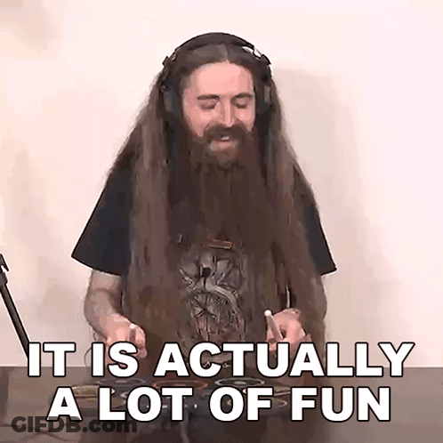 A Man With Long Hair And A Beard Is Playing Drums And Says " It Is Actually A Lot Of Fun " . GIF