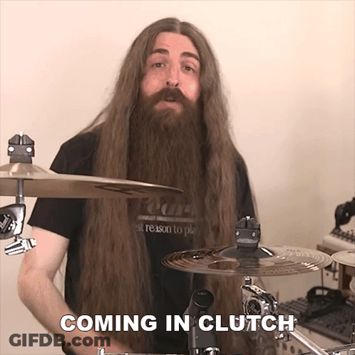 A Man With Long Hair And A Beard Is Playing Drums And The Words Coming In Clutch Are Above Him GIF