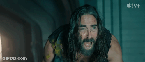 A Man With Long Hair And A Beard Is Screaming In Front Of An Apple Tv+ Sign GIF