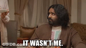 A Man With Long Hair And A Beard Is Sitting At A Table With A Laptop And A Plate Of Food . GIF