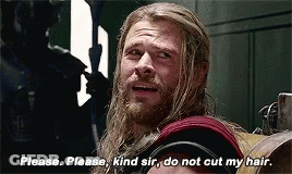 A Man With Long Hair And A Beard Is Sitting In A Chair And Talking To Another Man . GIF