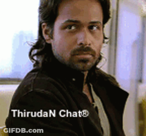 A Man With Long Hair And A Beard Is Sitting In A Chair With The Words Thiruda N Chat Written Below Him . GIF