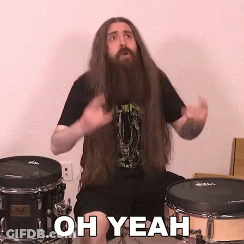 A Man With Long Hair And A Beard Is Sitting In Front Of A Drum Set And Saying Oh Yeah GIF