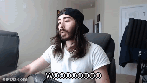 A Man With Long Hair And A Beard Is Sitting In Front Of A Microphone With The Words Wooooooo On The Bottom GIF