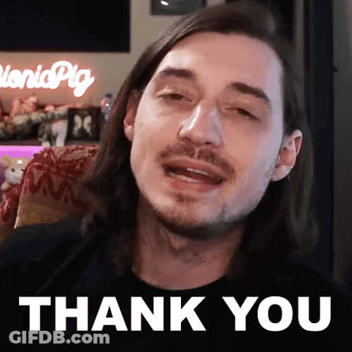 A Man With Long Hair And A Beard Is Sitting In Front Of A Thank You Sign GIF