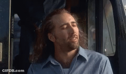 A Man With Long Hair And A Beard Is Sitting In The Driver 'S Seat Of A Car . GIF
