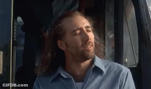 A Man With Long Hair And A Beard Is Sitting In The Driver 'S Seat Of A Truck With His Eyes Closed . GIF