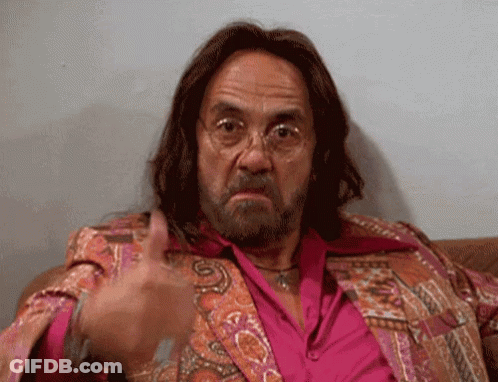 A Man With Long Hair And A Beard Is Sitting On A Couch And Giving A Thumbs Up GIF