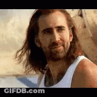A Man With Long Hair And A Beard Is Smiling And Wearing A White Tank Top . GIF