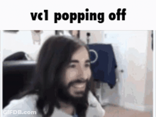 A Man With Long Hair And A Beard Is Smiling While Sitting In A Chair . GIF