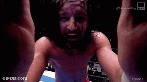 A Man With Long Hair And A Beard Is Standing In A Ring With His Arms In The Air . GIF