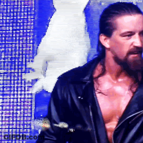 A Man With Long Hair And A Beard Is Standing In Front Of A Blue Background . GIF