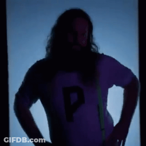 A Man With Long Hair And A Beard Is Standing In Front Of A Blue Background . GIF