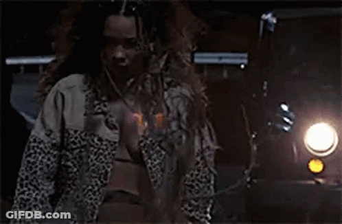 A Man With Long Hair And A Beard Is Standing In Front Of A Car At Night . GIF