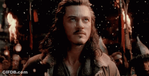 A Man With Long Hair And A Beard Is Standing In Front Of A Group Of People Holding A Torch . GIF