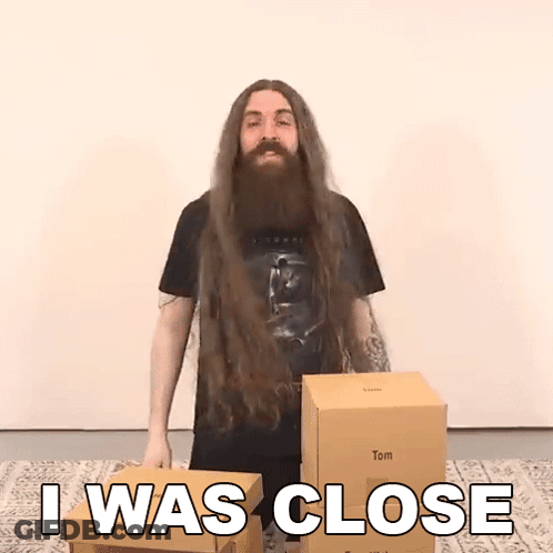 A Man With Long Hair And A Beard Is Standing Next To Boxes And Says I Was Close GIF