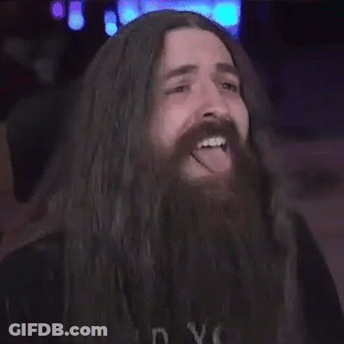 A Man With Long Hair And A Beard Is Sticking Out His Tongue . GIF