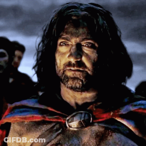 A Man With Long Hair And A Beard Is Wearing A Cape And A Medallion Around His Neck GIF