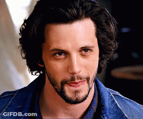 A Man With Long Hair And A Beard Is Wearing A Denim Jacket GIF