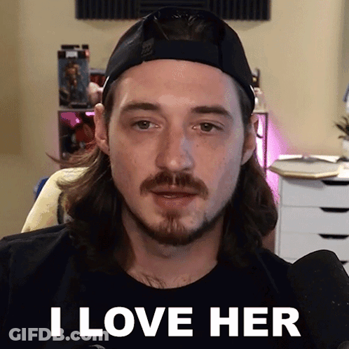 A Man With Long Hair And A Beard Is Wearing A Hat And Saying I Love Her GIF