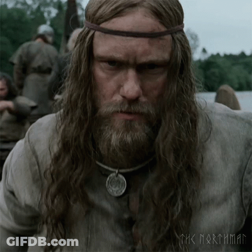 A Man With Long Hair And A Beard Is Wearing A Necklace And A Headband With The Words The Northman On It GIF
